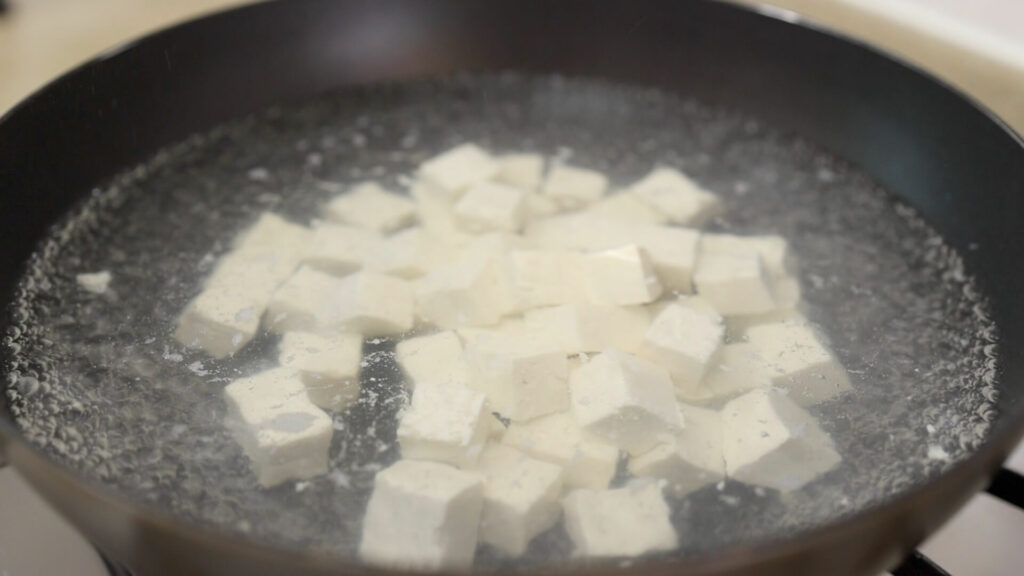 Blanch tofu in a wok