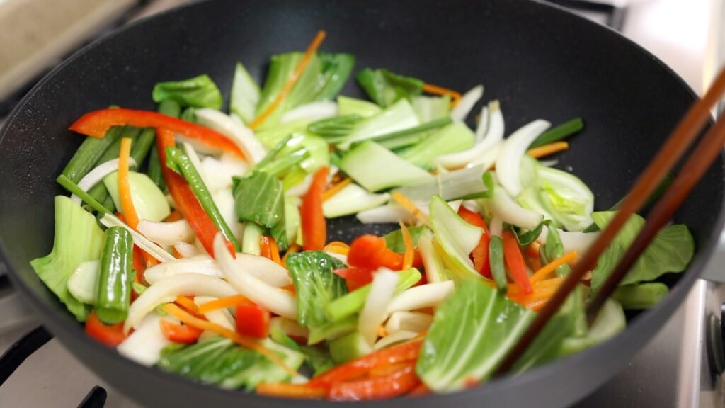 Stir-fry vegetables in a wok
