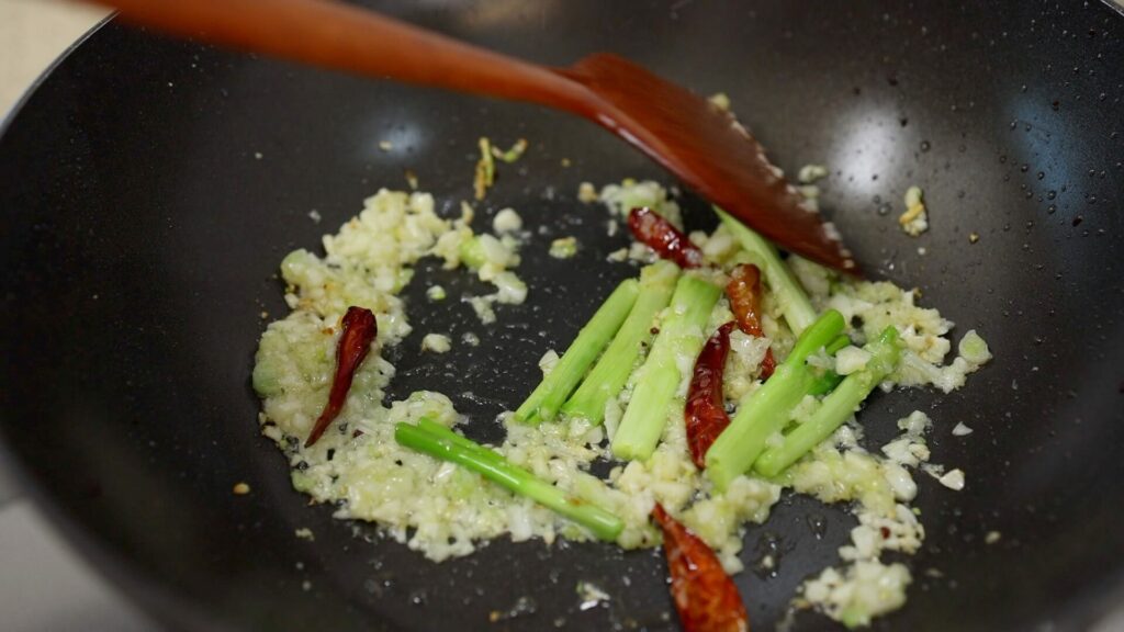 Cook garlic, green onion, and chili in a wok